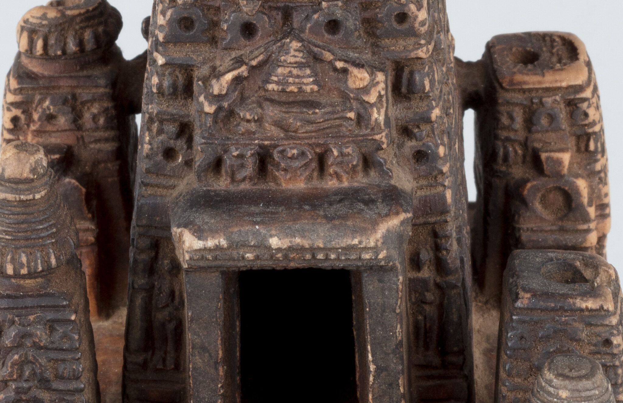 Close view of carved pediment and doorway situated on tapered roof of architectural model