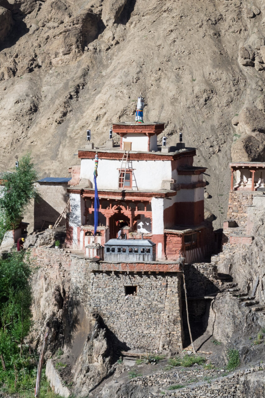 Comprehensive view of multi-story white building with red trim perched on hilltop before rocky, eroded mountainside