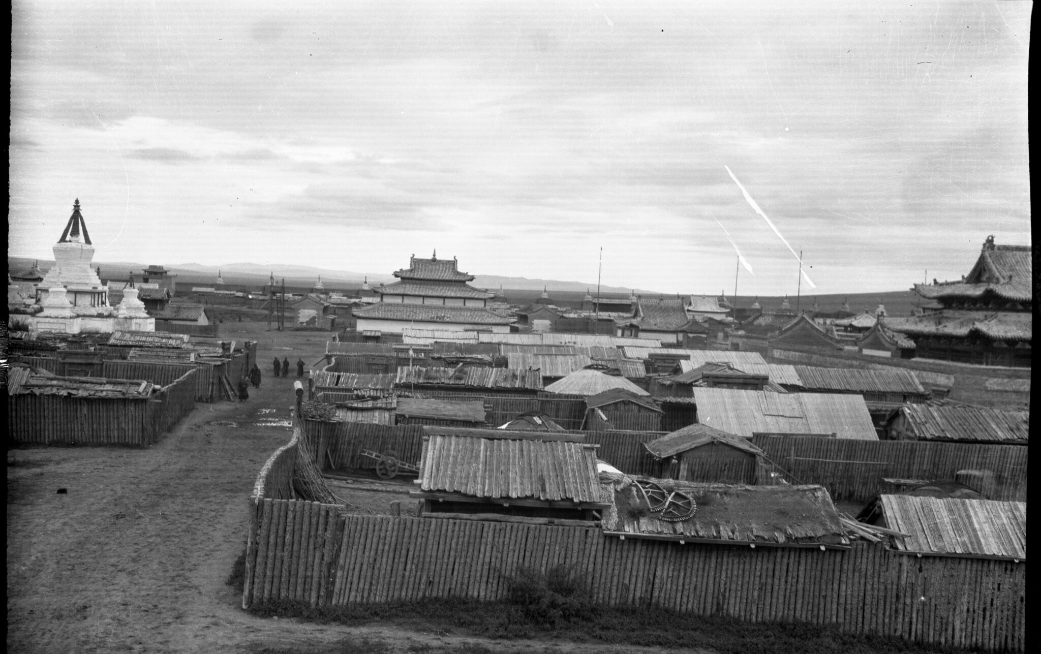 Black and white photograph of temple complex dominated by white stupa at left and pagoda-roofed buildings at center and right