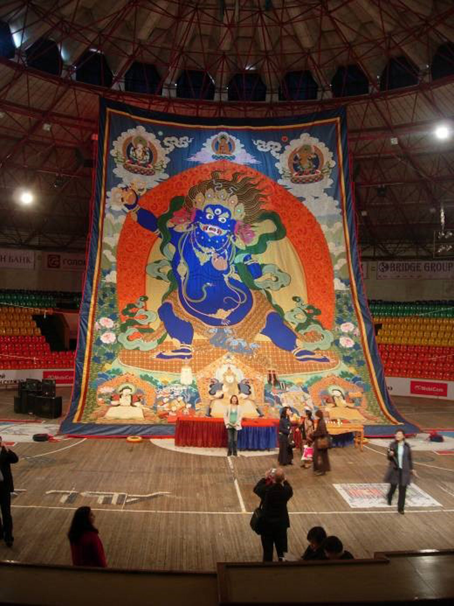 Monumental textile hung from rafters of sporting arena depicting blue-skinned wrathful deity