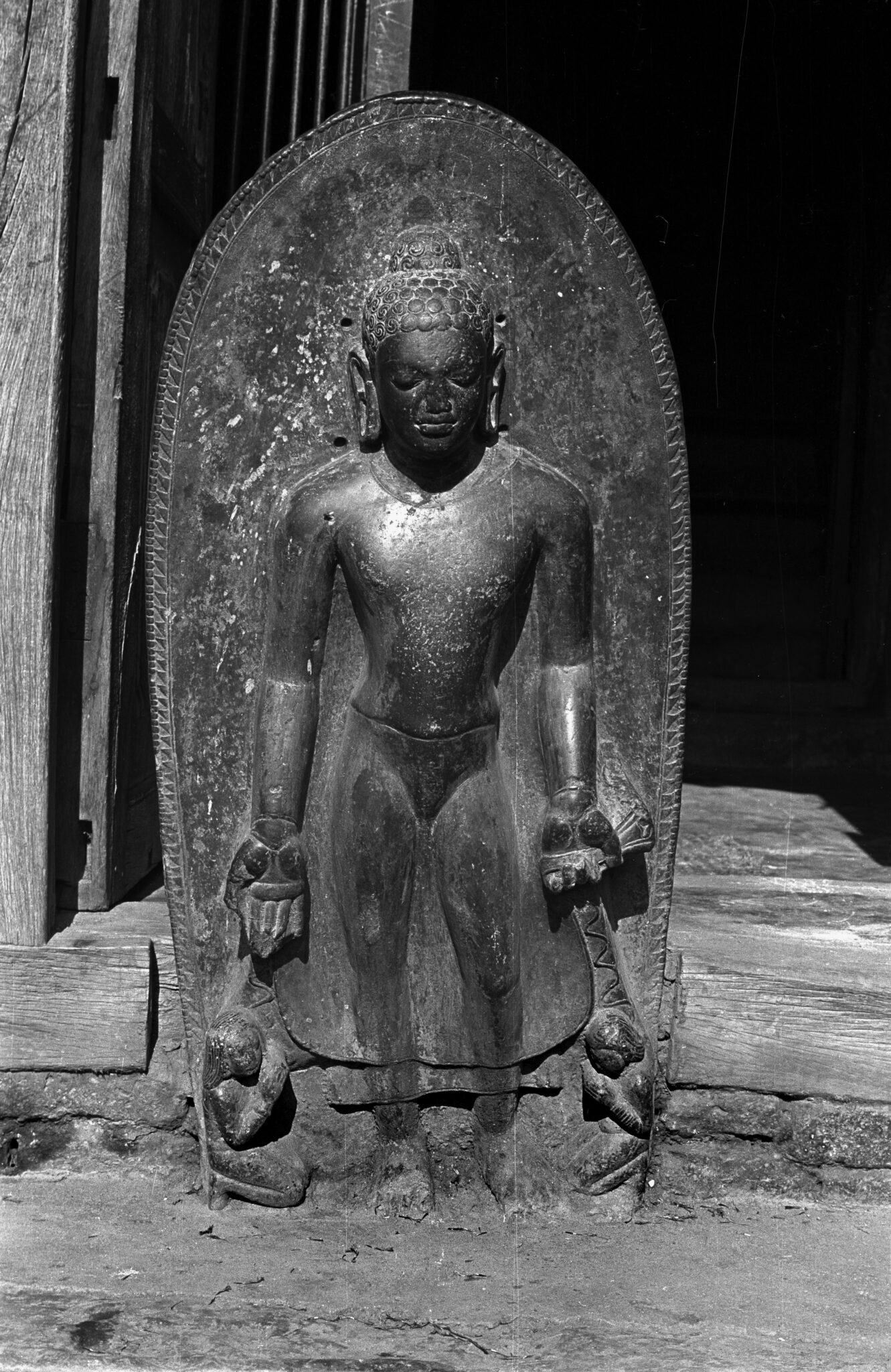 Black and white photograph of relief sculpture depicting Buddha flanked by two kneeling attendants