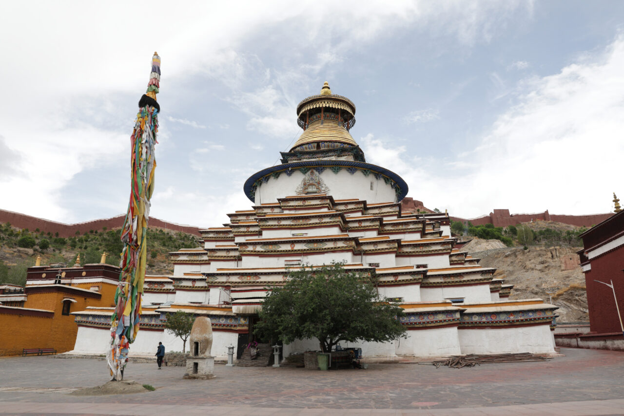 Stepped pyramid structure featuring articulated eaves topped with short cylindrical tower and golden conical ornament with canopy