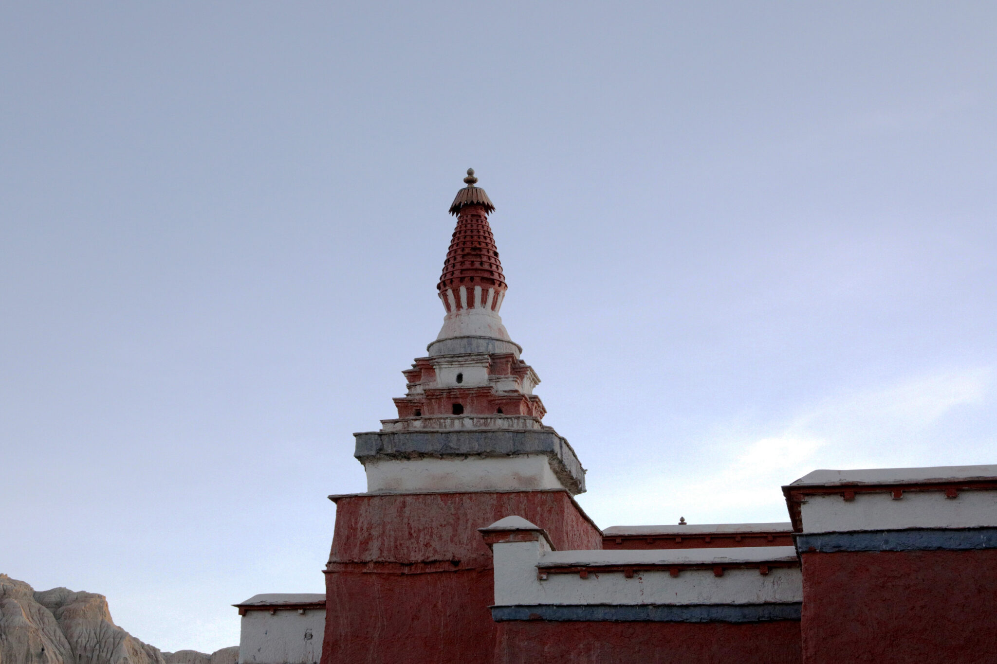 Twilight view of densely articulated stupa at corner of red building featuring blue and white trim