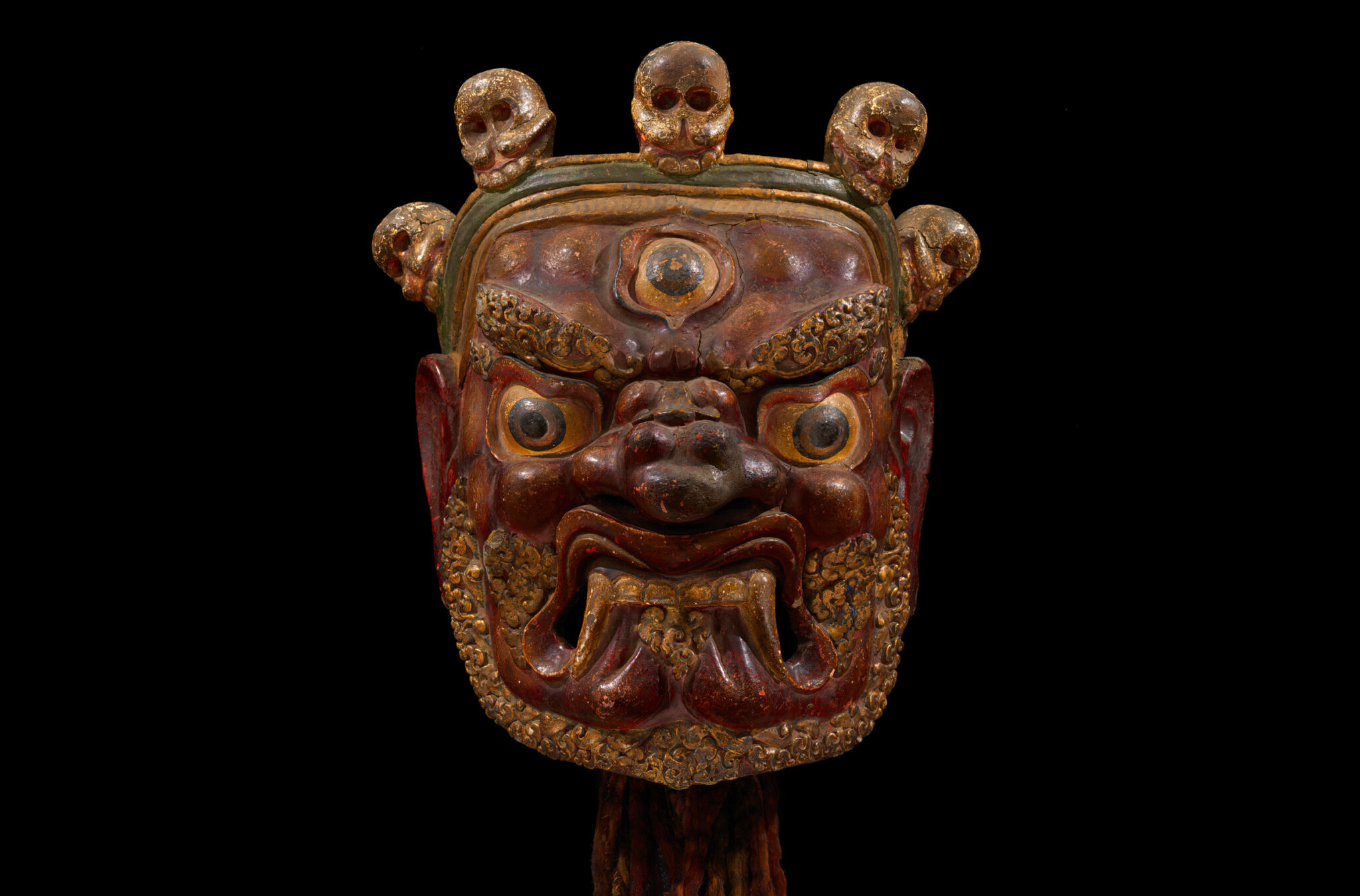 Mask depicting wrathful deity with third eye and bared teeth; features five-skull crown and filigreed beard