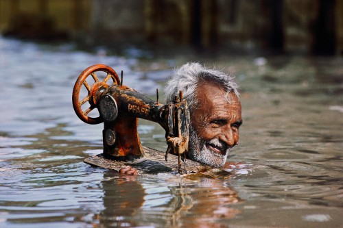 Steve McCurry; Tailor Carries His Sewing Machine through Monsoon Waters; Porbandar, Gujarat, India; 1983 