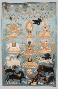 Embroidered white and black animals, two black ravens, and human figures populate a light blue background. Skulls and beaded strings decorate the upper edge, with black animals in the lower portion. A dark, blue-skinned figure sits at center, one of three human figures. There are seven animals, including a white Bactrian camel and a black snow lion devouring a corpse. All represent symbolic offerings.