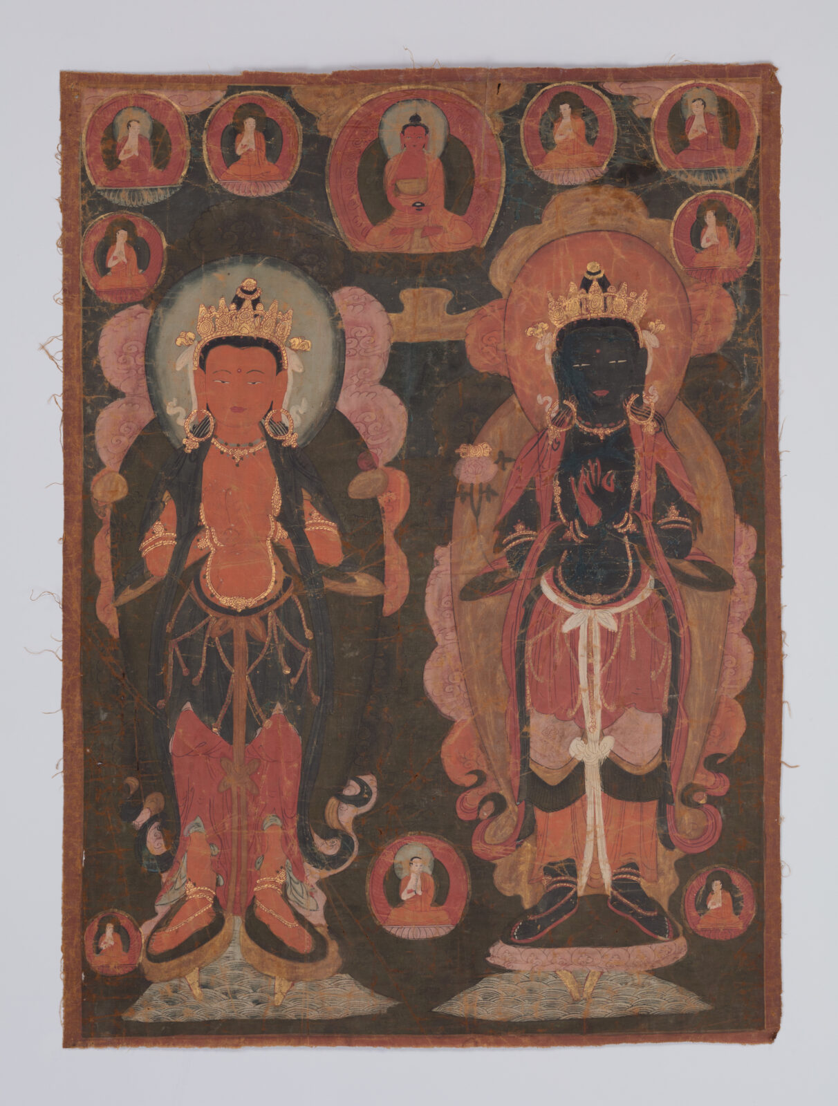 Two richly dressed figures stand side-by-side, facing frontally, against a dark background. Smaller seated figures of monks in circular motifs appear at the upper and lower portions of the painting.