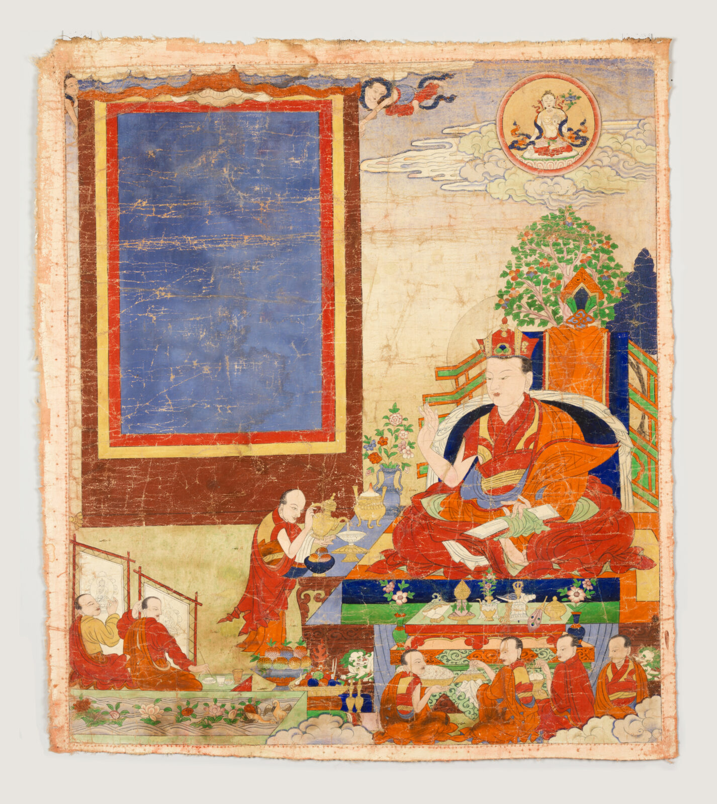 Rectangular, aged painting showing a seated teacher in red and orange robes surrounded by smaller figures in similar robes, with a small deity above and a large blue panel at left.