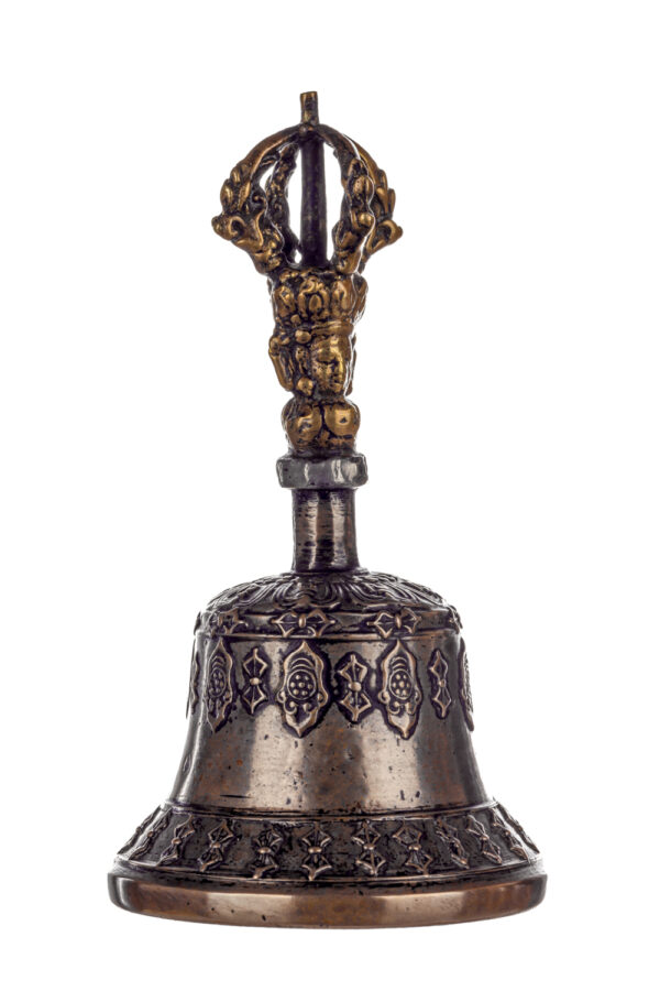 Metal bell with detailed engravings. The handle has a human head below a double-ended, symmetrical structure resembling four crescent moons that meet at the top.