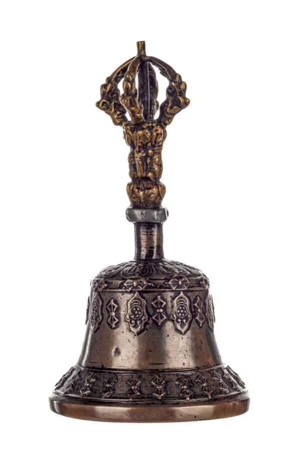 Metal bell with detailed engravings. The handle has a human head below a double-ended, symmetrical structure resembling four crescent moons that meet at the top.