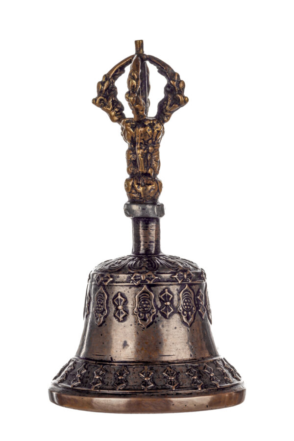 Metal bell with detailed engravings. The handle has a human head below a double-ended, symmetrical structure resembling four crescent moons that meet at the top.