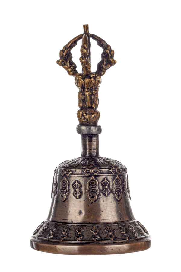 Metal bell with detailed engravings. The handle has a human head below a double-ended, symmetrical structure resembling four crescent moons that meet at the top.