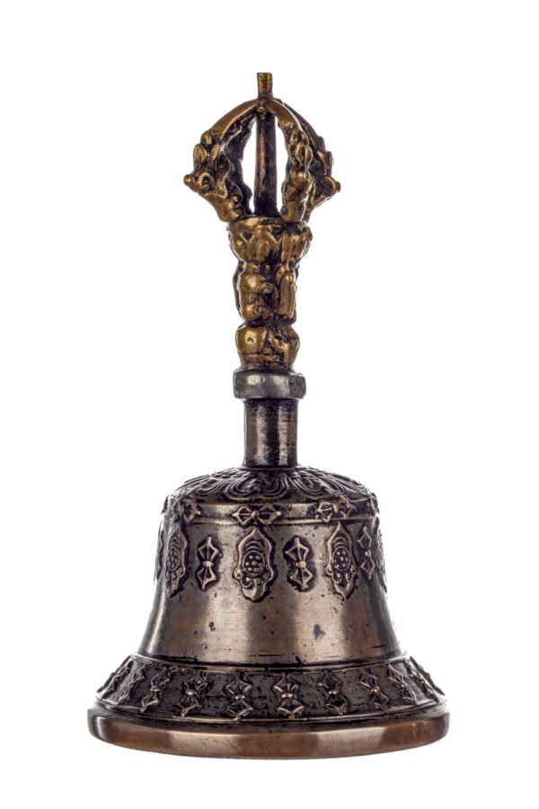 Metal bell with detailed engravings. The handle has a human head below a double-ended, symmetrical structure resembling four crescent moons that meet at the top.