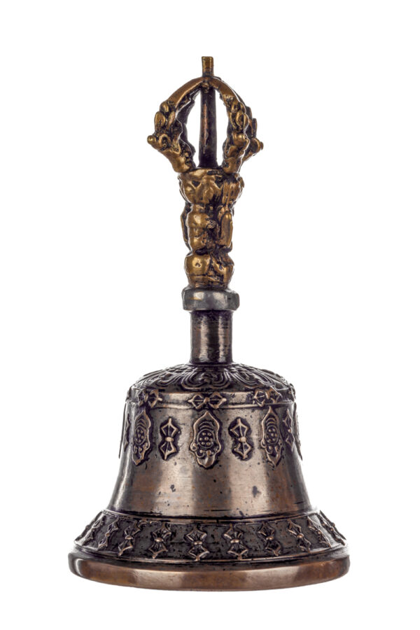 Metal bell with detailed engravings. The handle has a human head below a double-ended, symmetrical structure resembling four crescent moons that meet at the top.