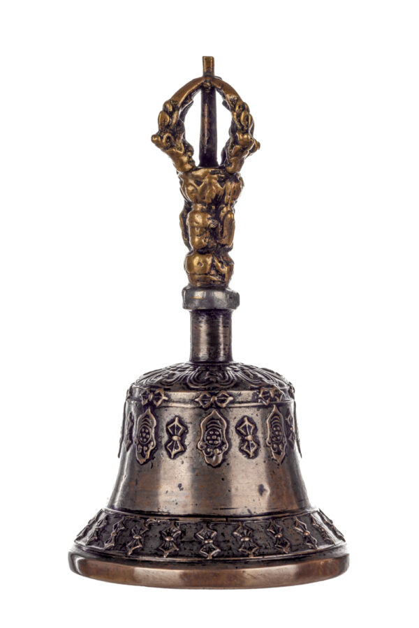 Metal bell with detailed engravings. The handle has a human head below a double-ended, symmetrical structure resembling four crescent moons that meet at the top.