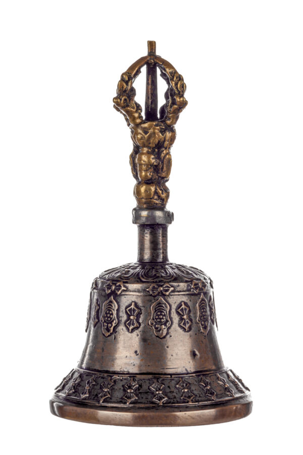 Metal bell with detailed engravings. The handle has a human head below a double-ended, symmetrical structure resembling four crescent moons that meet at the top.