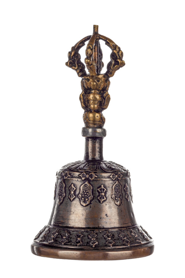 Metal bell with detailed engravings. The handle has a human head below a double-ended, symmetrical structure resembling four crescent moons that meet at the top.