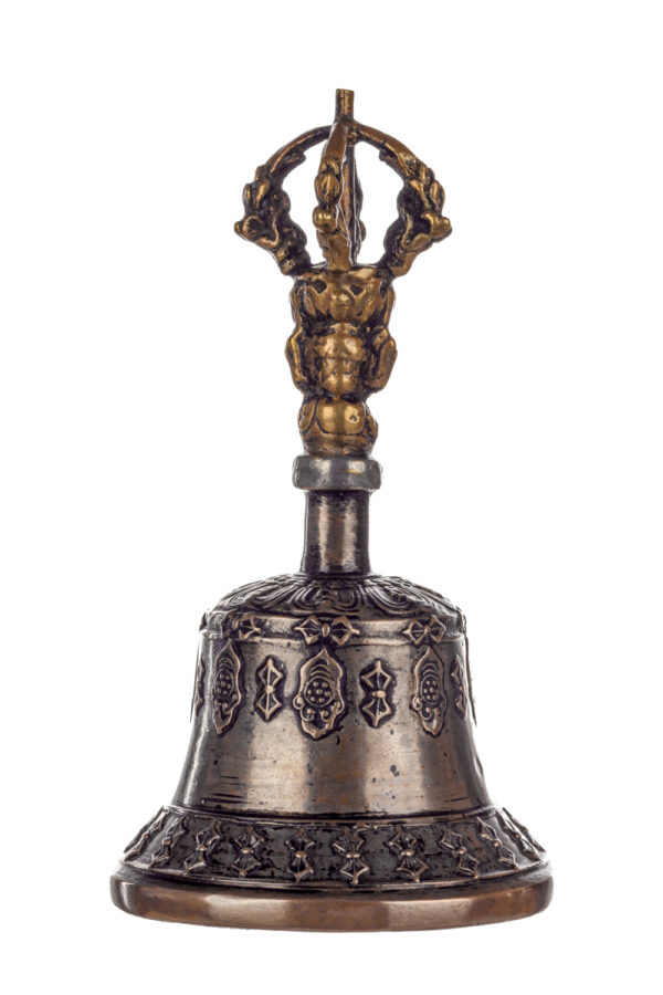 Metal bell with detailed engravings. The handle has a human head below a double-ended, symmetrical structure resembling four crescent moons that meet at the top.