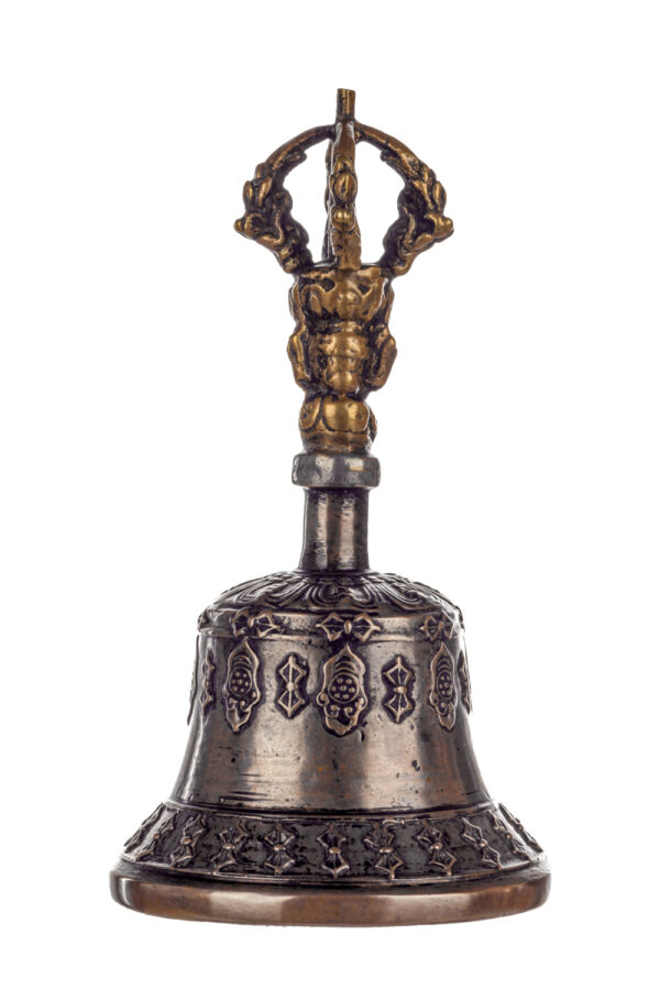 Metal bell with detailed engravings. The handle has a human head below a double-ended, symmetrical structure resembling four crescent moons that meet at the top.