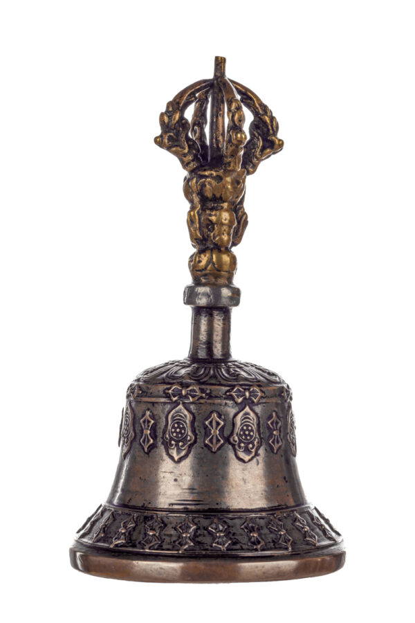 Metal bell with detailed engravings. The handle has a human head below a double-ended, symmetrical structure resembling four crescent moons that meet at the top.