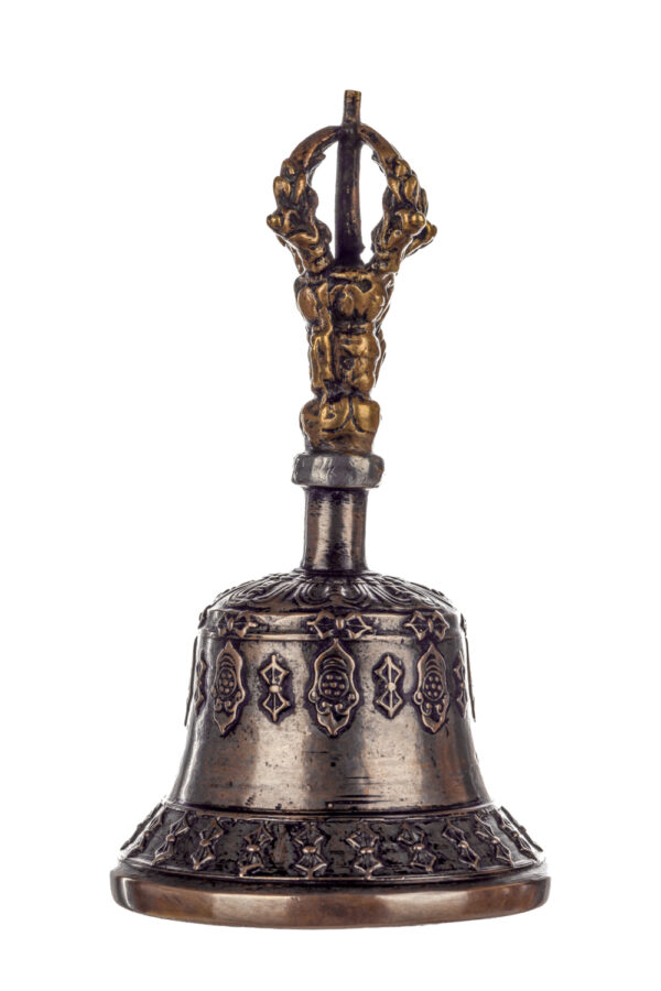 Metal bell with detailed engravings. The handle has a human head below a double-ended, symmetrical structure resembling four crescent moons that meet at the top.