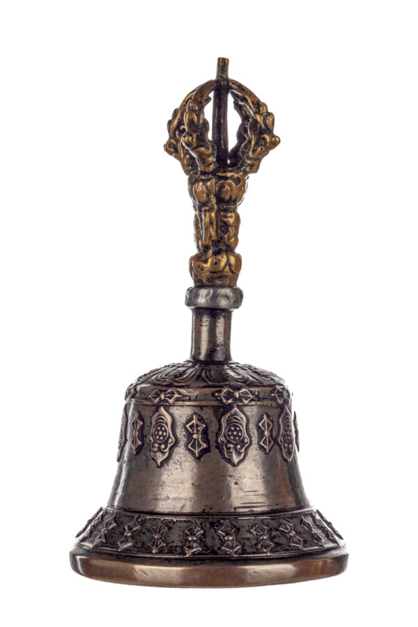 Metal bell with detailed engravings. The handle has a human head below a double-ended, symmetrical structure resembling four crescent moons that meet at the top.