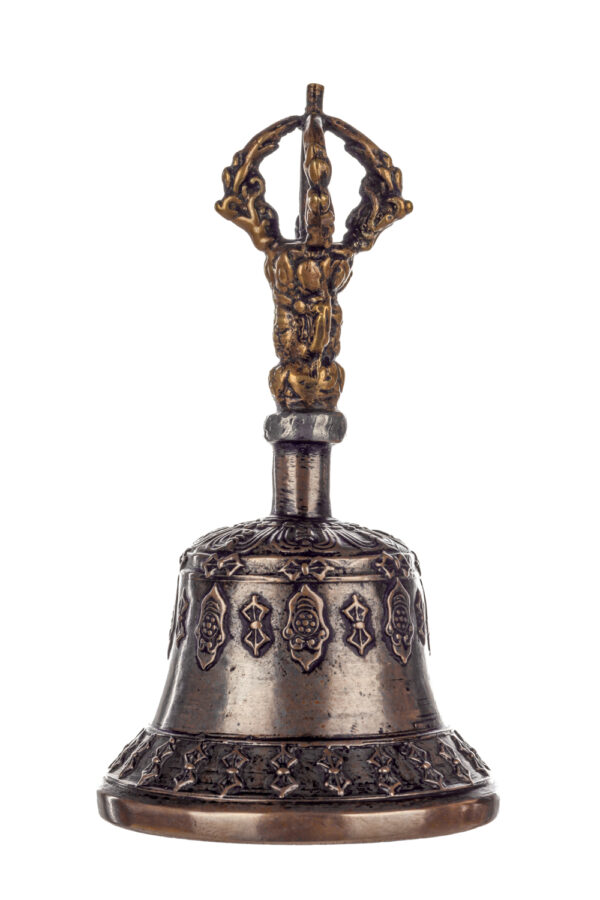 Metal bell with detailed engravings. The handle has a human head below a double-ended, symmetrical structure resembling four crescent moons that meet at the top.