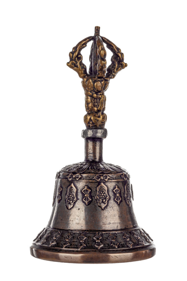 Metal bell with detailed engravings. The handle has a human head below a double-ended, symmetrical structure resembling four crescent moons that meet at the top.