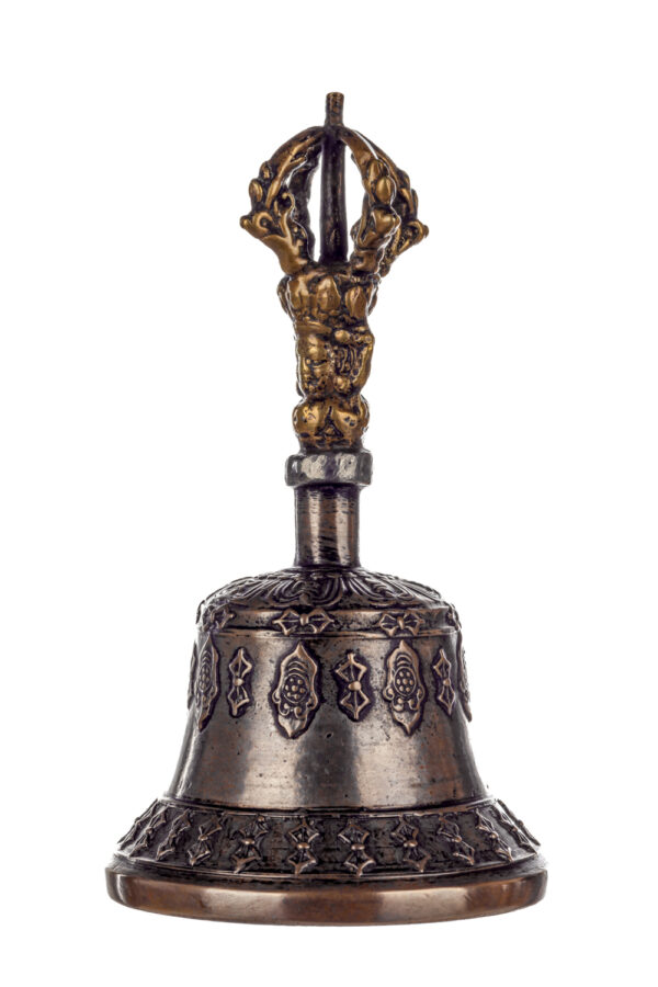 Metal bell with detailed engravings. The handle has a human head below a double-ended, symmetrical structure resembling four crescent moons that meet at the top.