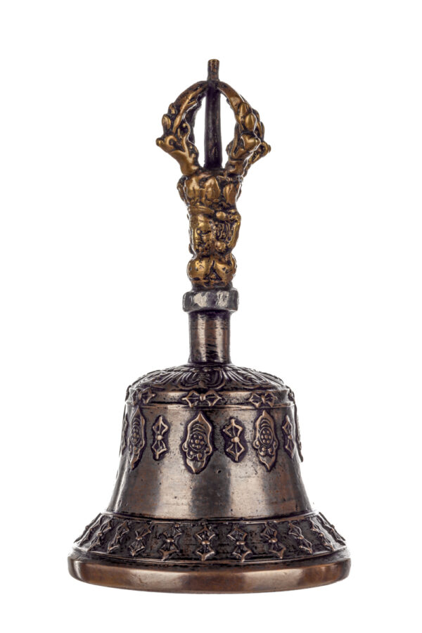 Metal bell with detailed engravings. The handle has a human head below a double-ended, symmetrical structure resembling four crescent moons that meet at the top.