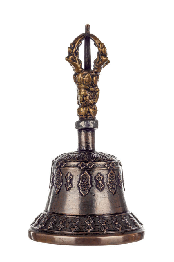 Metal bell with detailed engravings. The handle has a human head below a double-ended, symmetrical structure resembling four crescent moons that meet at the top.