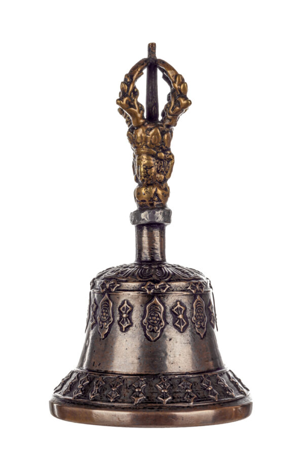 Metal bell with detailed engravings. The handle has a human head below a double-ended, symmetrical structure resembling four crescent moons that meet at the top.