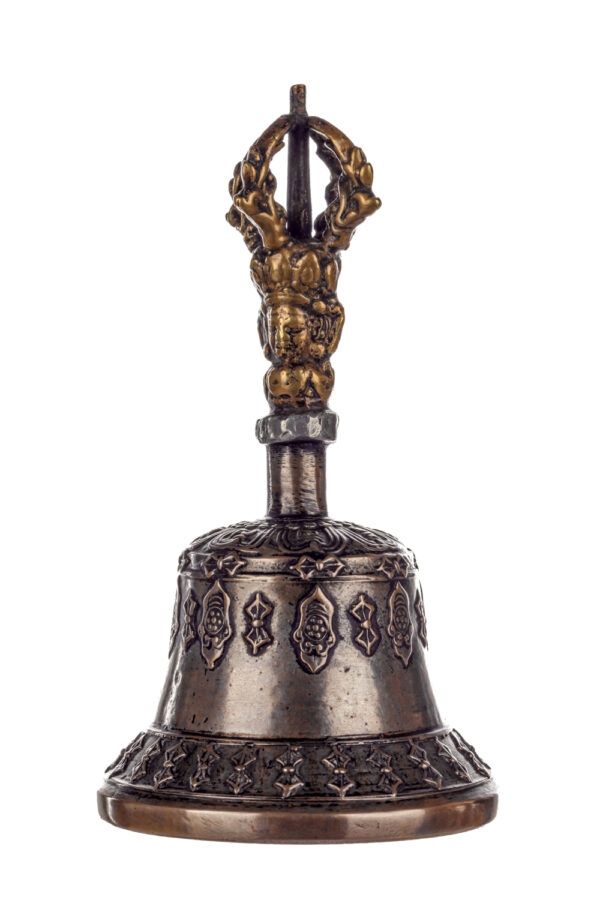 Metal bell with detailed engravings. The handle has a human head below a double-ended, symmetrical structure resembling four crescent moons that meet at the top.