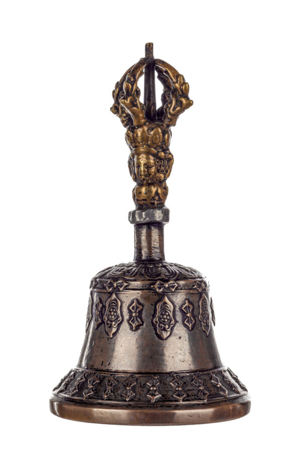 Metal bell with detailed engravings. The handle has a human head below a double-ended, symmetrical structure resembling four crescent moons that meet at the top.