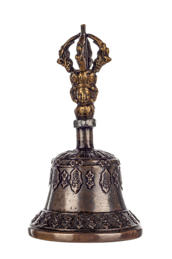 Metal bell with detailed engravings. The handle has a human head below a double-ended, symmetrical structure resembling four crescent moons that meet at the top.