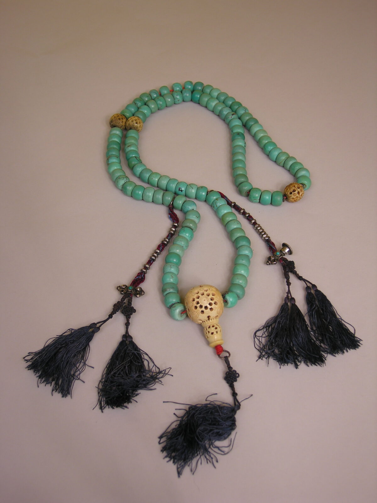 String of turquoise prayer beads with five black tassles.