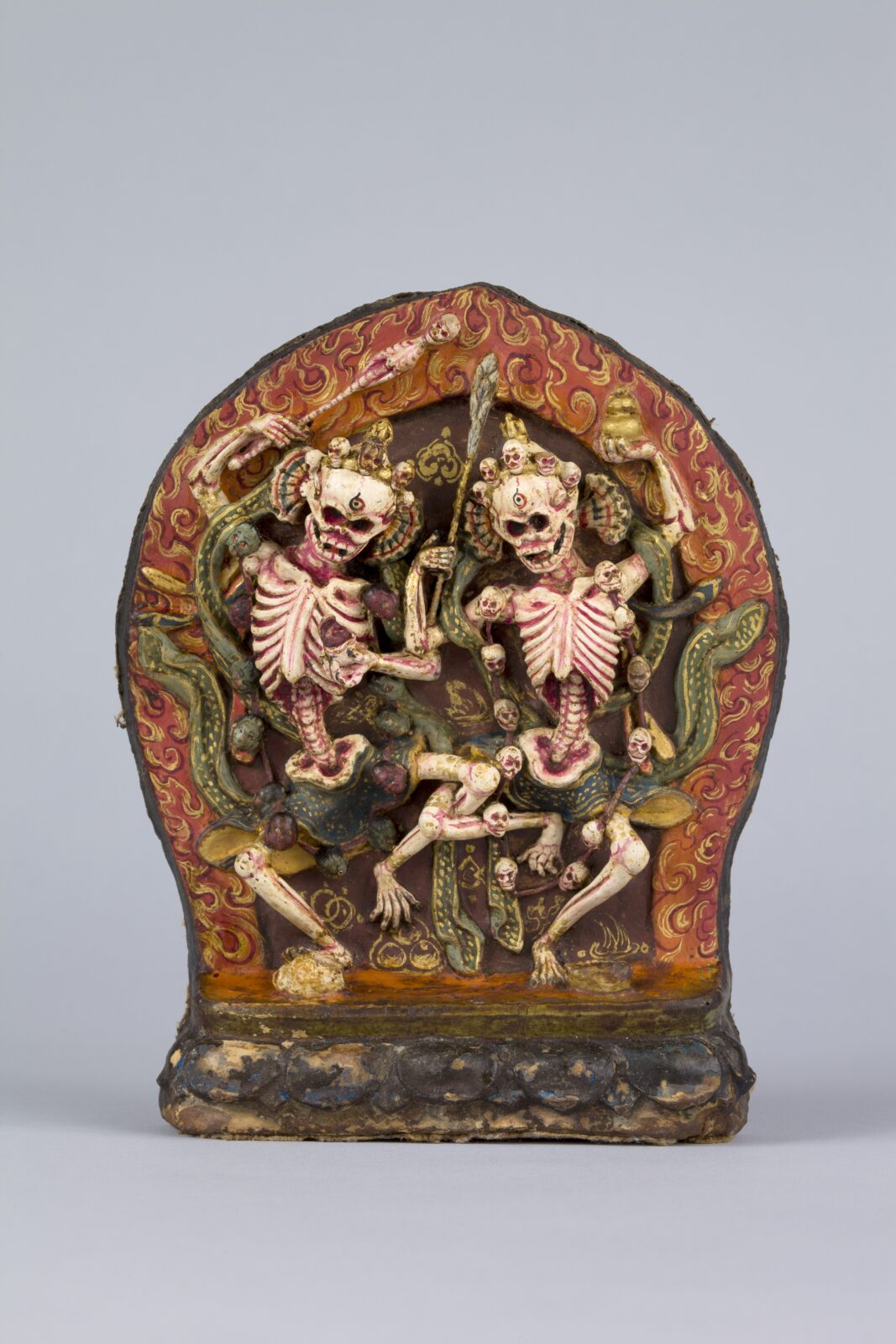 Painted sculpture of two dancing skeletons encircled by red flames.