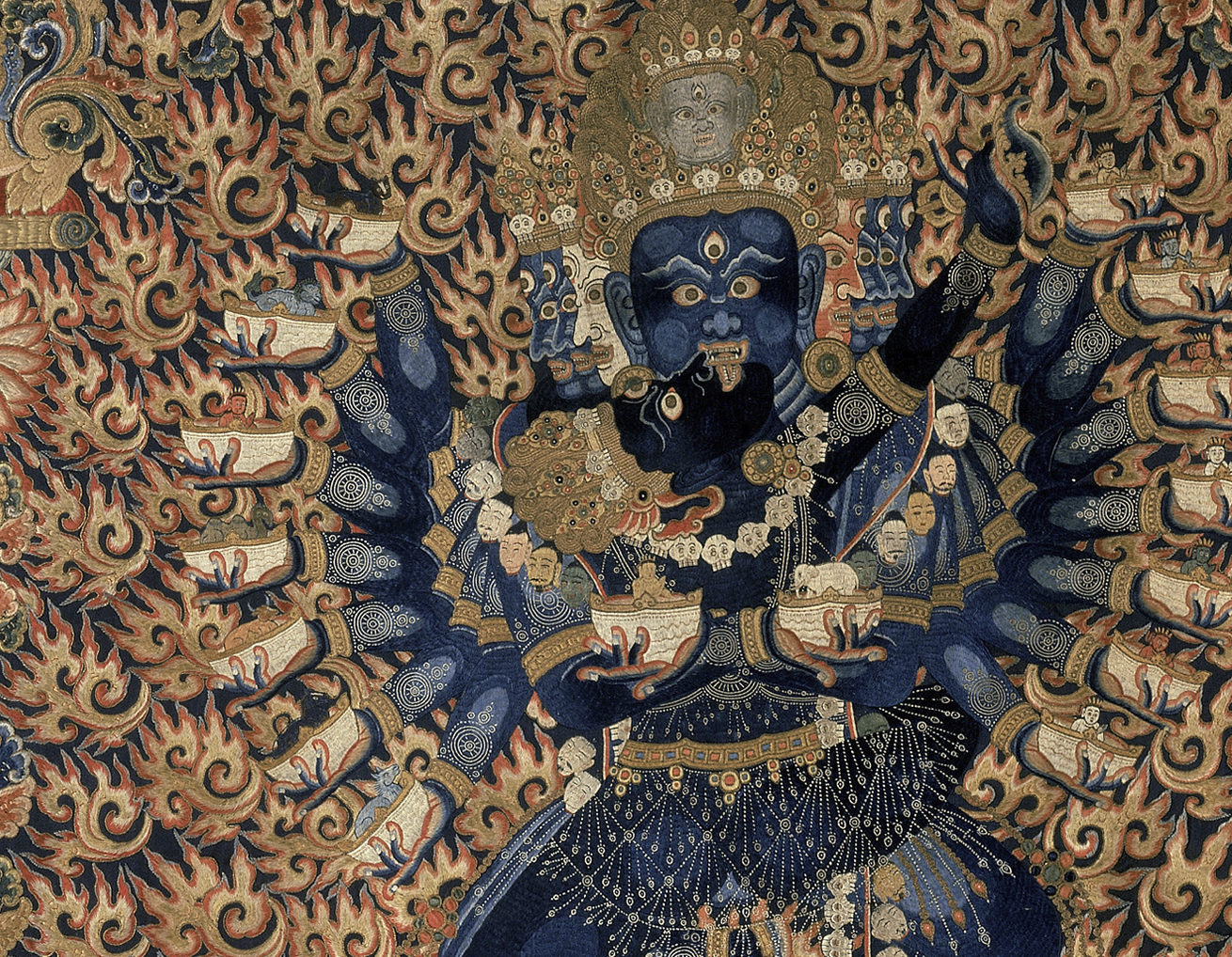 Tapestry of many-armed blue figure surrounded by golden flames.