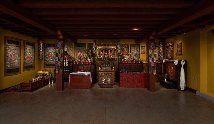 Shrine with many paintings on three walls, many small golden statues, and many wooden cabinets.