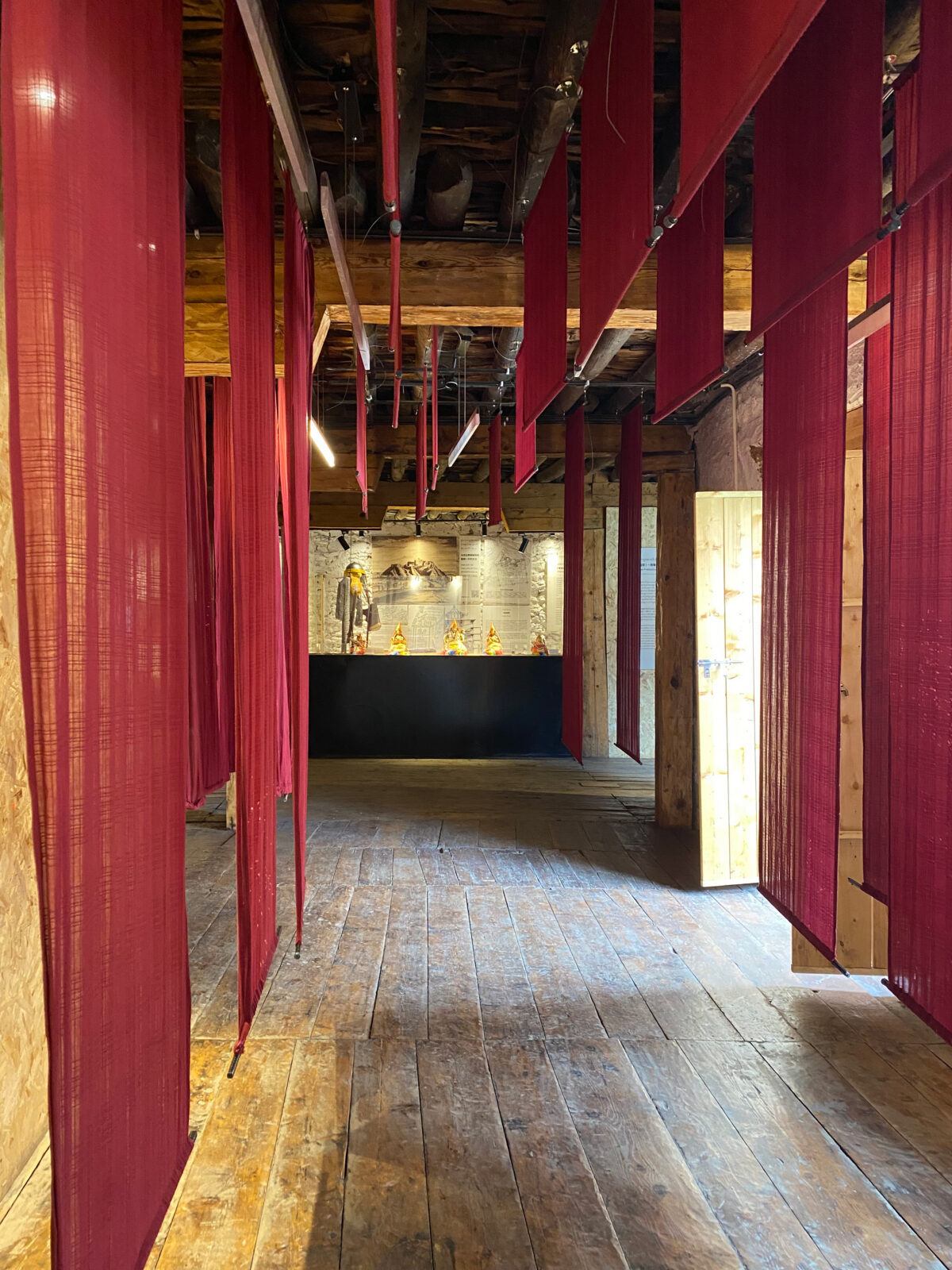 Interior of a building with wood floors and walls and red banners hanging from the ceiling