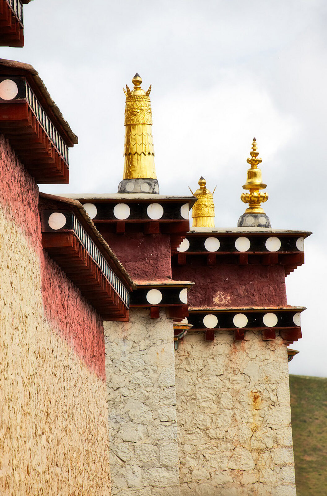 Brown brick building with red trimming and three golden sculptures at the corner