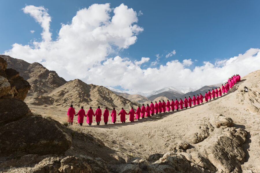 A group of people standing side by side, holding hands, and wearing pink robes at Disko Valley