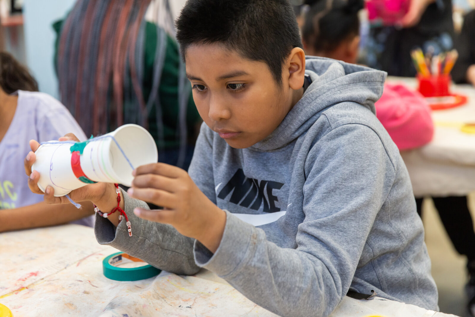student looking closely at an art project in progress