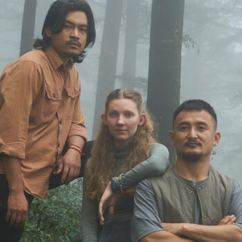 three people posing in the woods