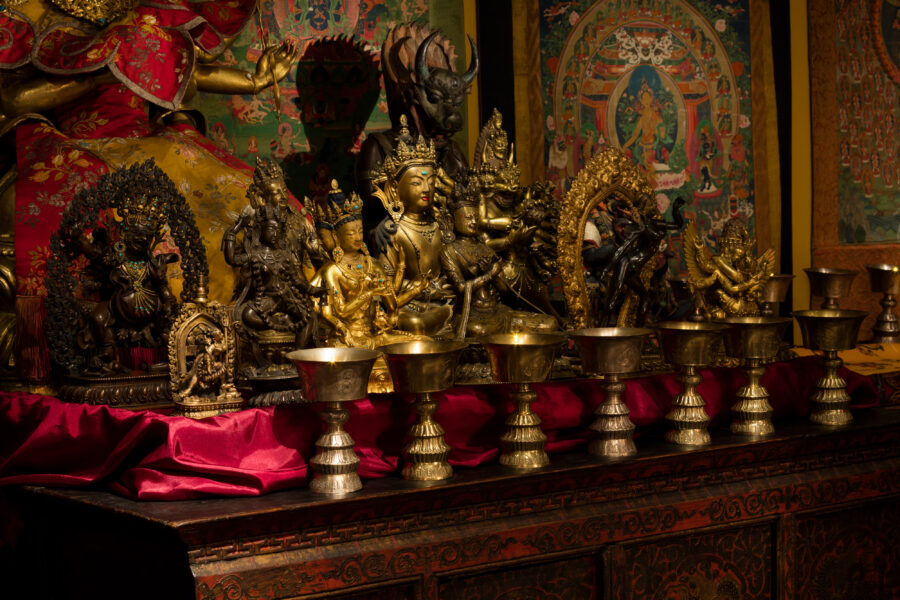 butter lamps and sculptures sit on top of a cabinet in the tibetan buddhist shrine room installation