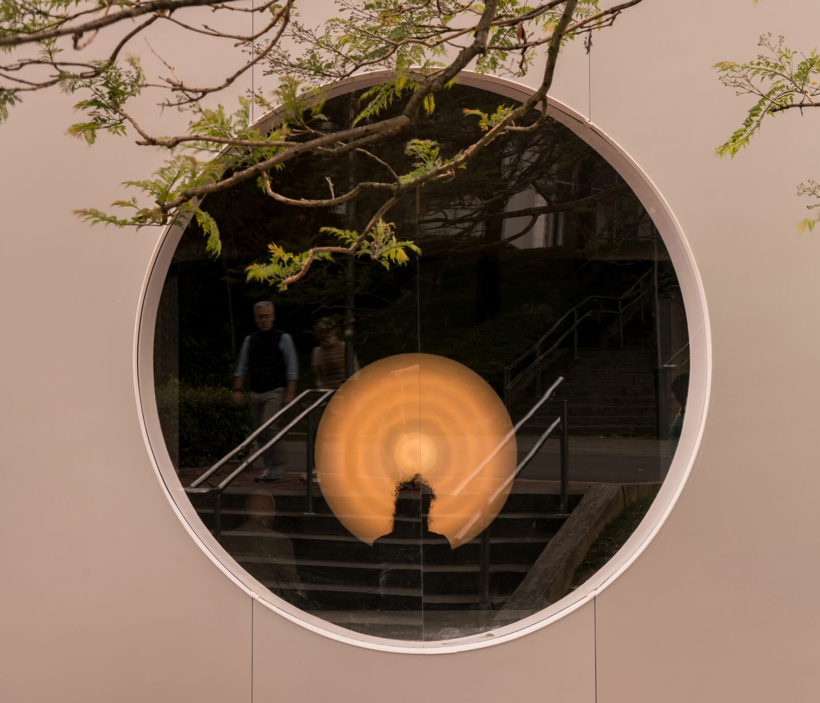 View from outside looking into round window with glowing circular object visible.