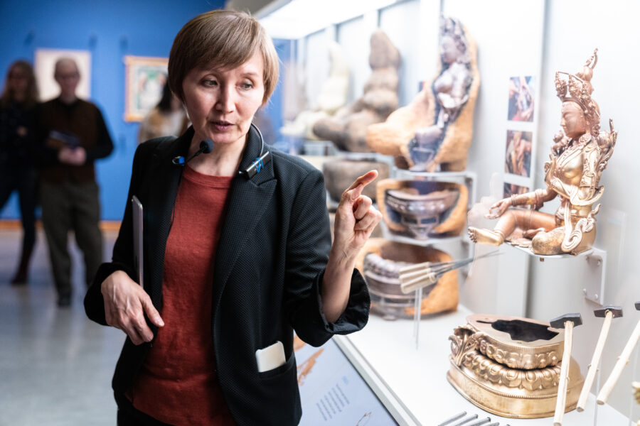 Image of curator standing in front of glass case with sculptures inside