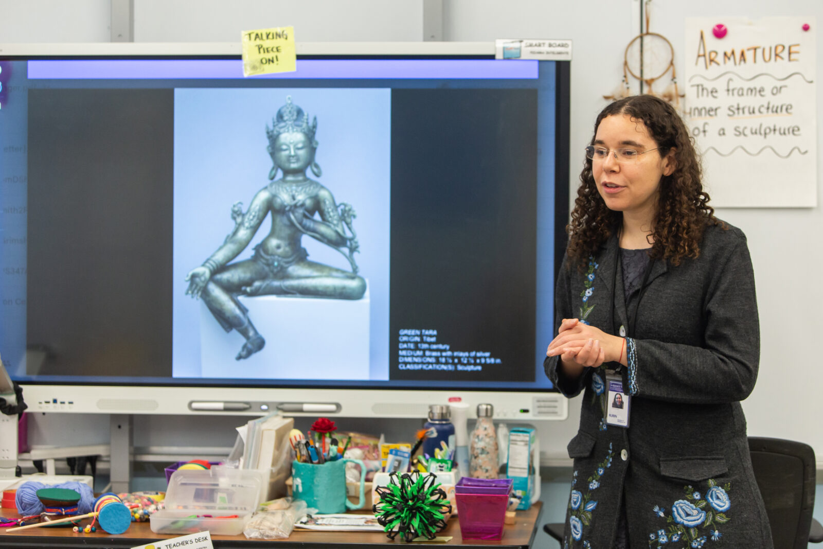 teaching artist standing in front of a projection of a Himalayan art object