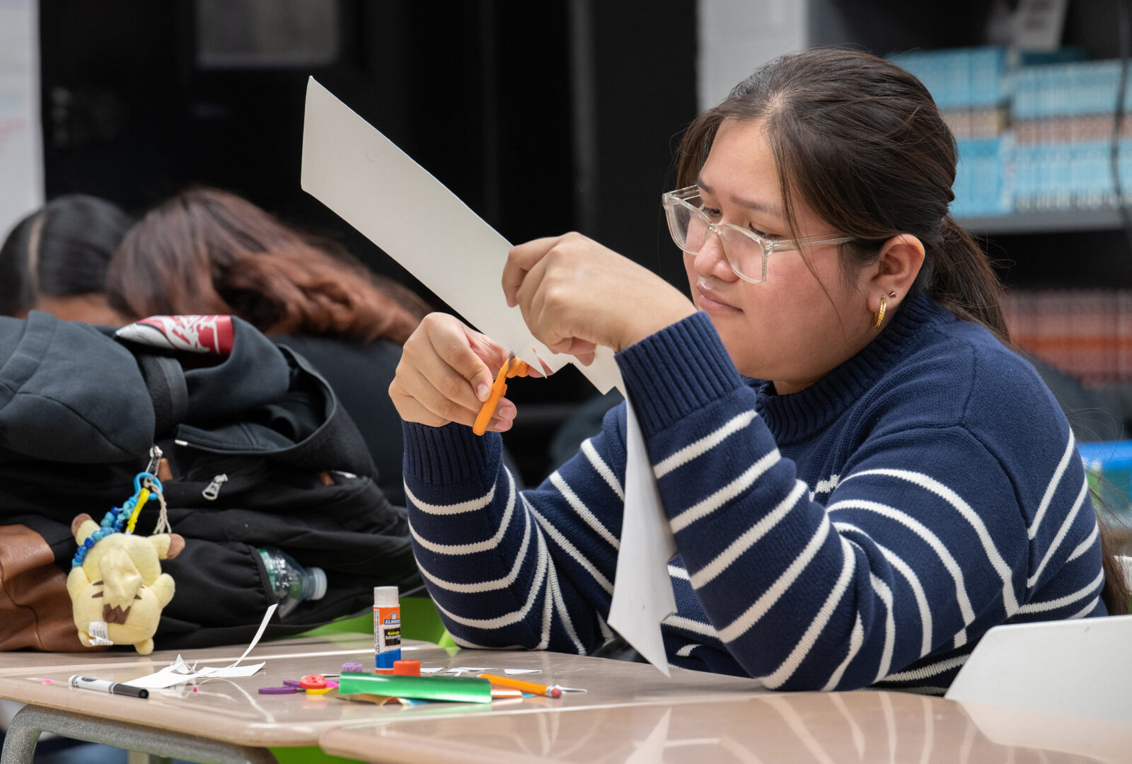 student concentrated on cutting paper in the classroom