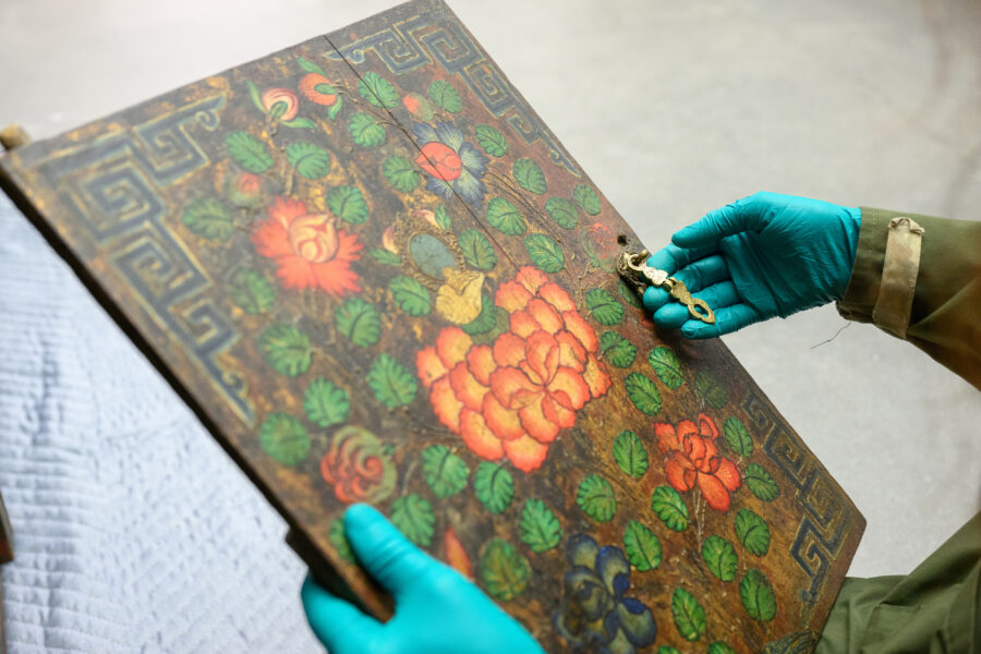 Close up of gloved hands holding the door of an altar cabinet.